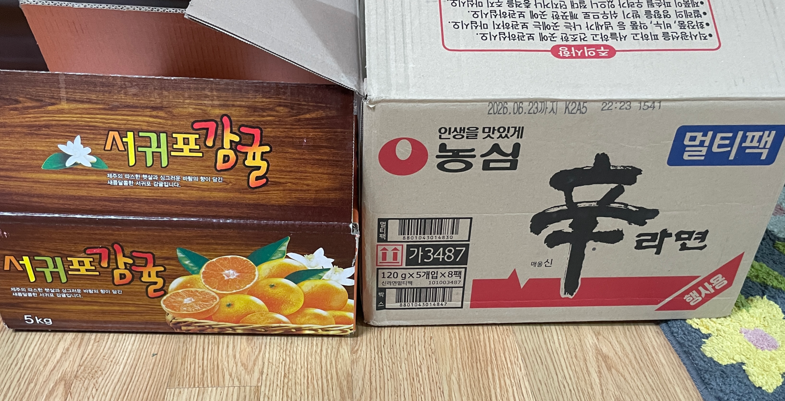 네이버 스토어에서 구입한 서귀포 감귤 박스와 농심 신라면 박스가 나란히 있어요.