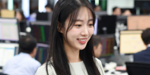 코스피 5000 돌파 주식 시장, 증권사 객장에서 여성이 웃는 얼굴로 컴퓨터 모니터를 바라보고 있습니다.
