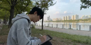 아이패드 드로잉 공부 중 남성이 한강 공원에서 애플펜슬로 드로잉 연습 중이다