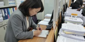 이사 당일 전입신고 30대 여성, 창구 앞에서 펜으로 전입신고서류 작성한다